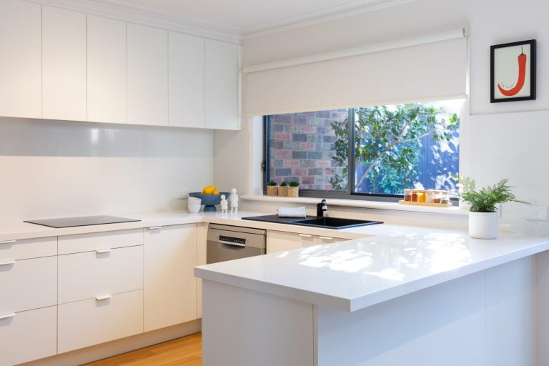 white u shaped kitchen with black sink and tap and white stone benchtops