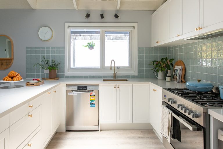 White u shaped kitchen with shaker cabinetry and dishwasher positioned to the left of the sink underneath kitchen window
