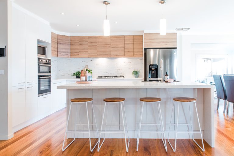 L shape kitchen in white gloss cabinetry with timber look overhead cabinetry and island bench for entertaining