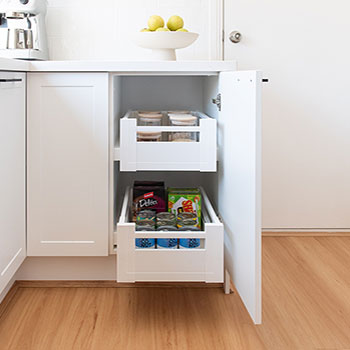 white kitchen cabinetry featuring slide out drawers that hold tins of food and staples