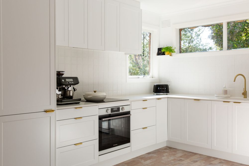 White l shaped shaker style kitchen in home in Oakleigh