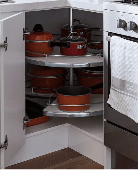 Large lazy susan in corner cabinet featuring six red pots and pans