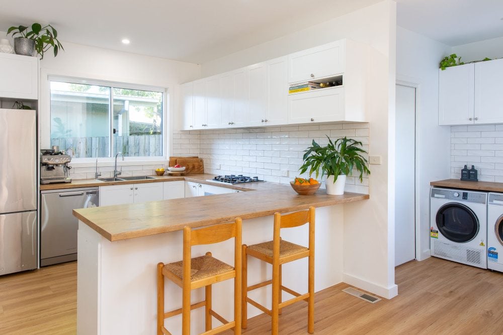 White shaker style u shaped kitchen with island bench and galley laundry