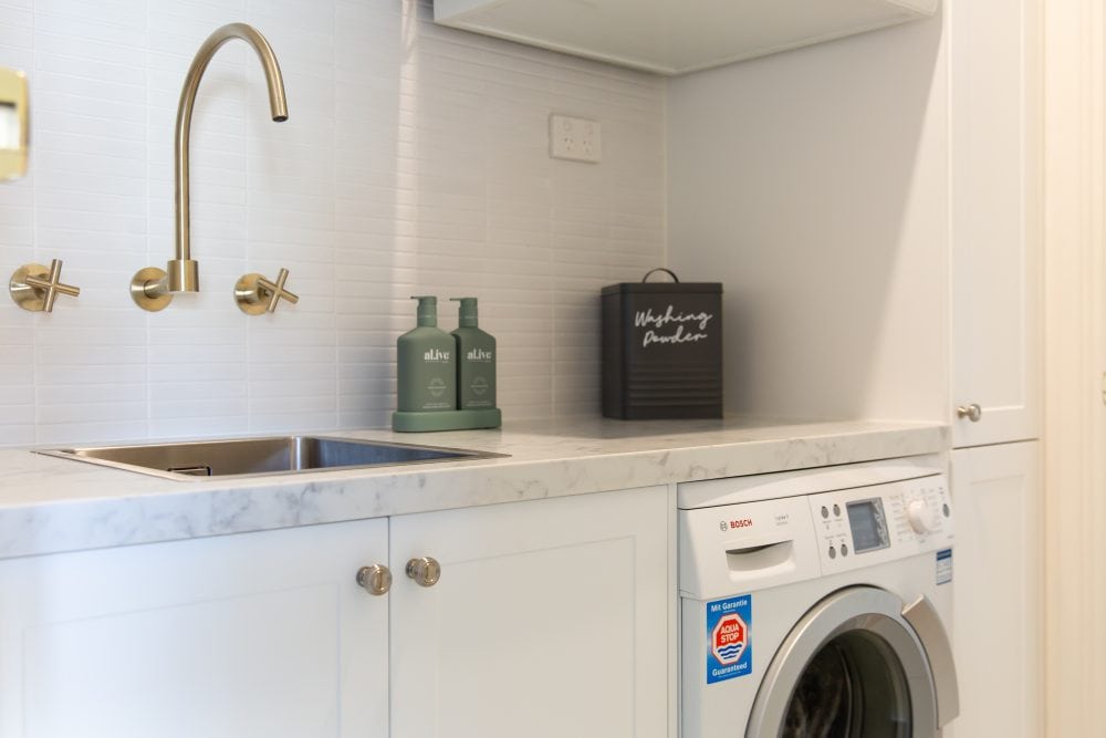 White laundry with brass tapware and washing detergents