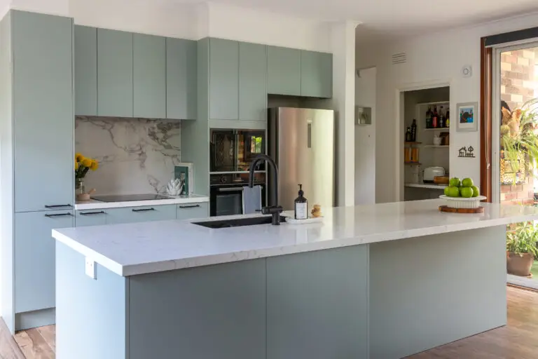 Light green colour kitchen cabinetry in galley kitchen with tall pantry and large island bench