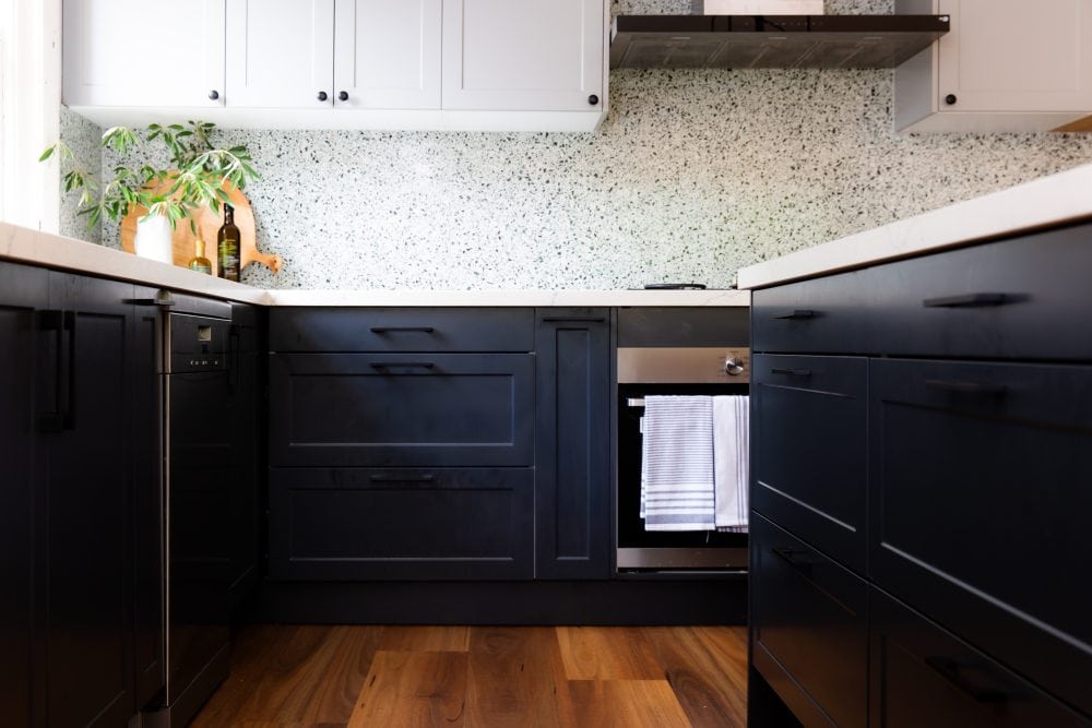 Dark bold grey kitchen cabinetry with white shaker overheads matched with terazzo tiles and and timber flooring
