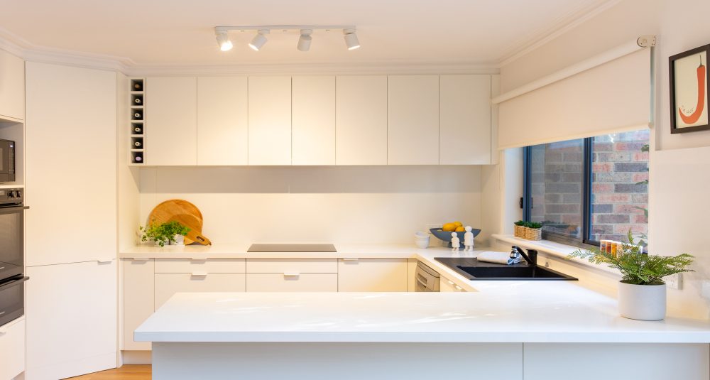 White cabinetry with white benchtops in a u shaped kitchen