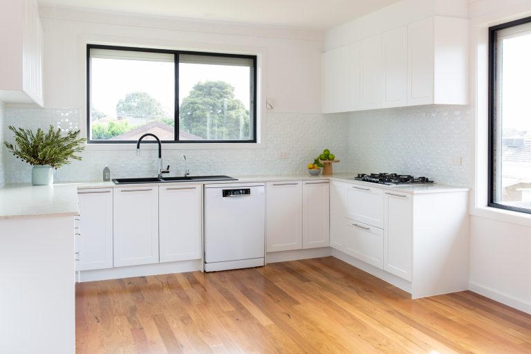 White u shaped kitchen with black window and black appliances