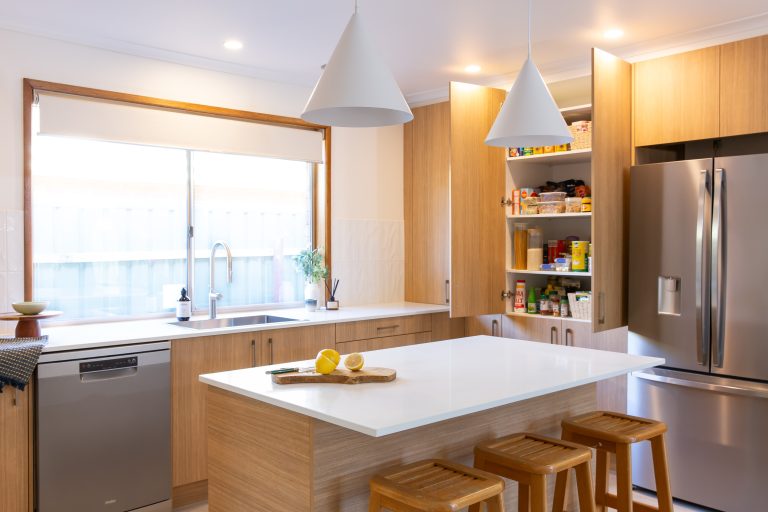 U-Shaped kitchen featuring warm timber laminate cabinetry and pantry open to display pantry items
