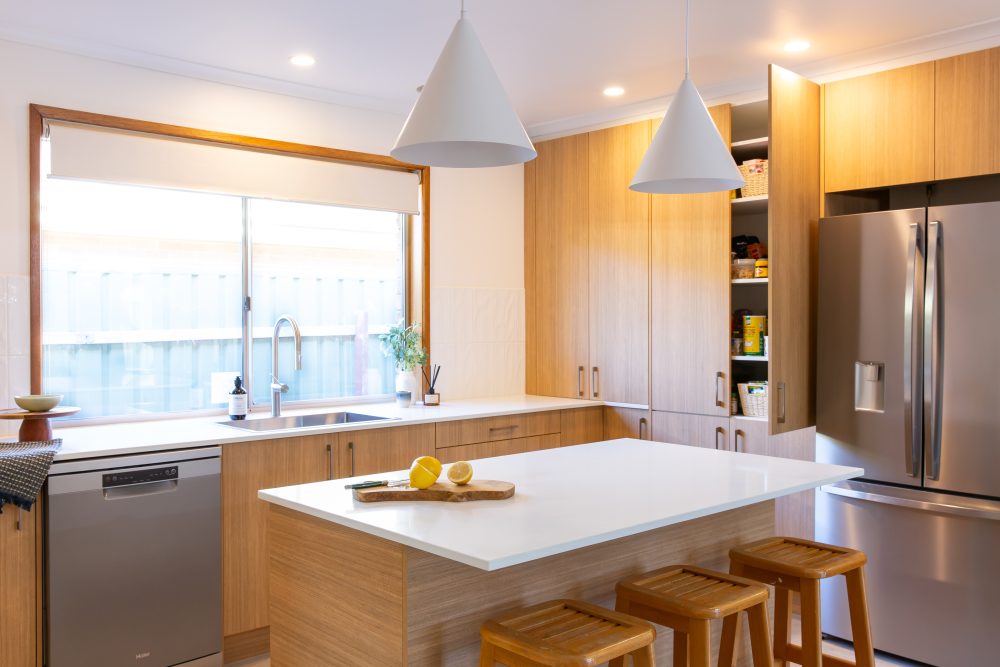 Oak timber cabinetry in a u shape kitchen with a standalone island bench with three bench stools