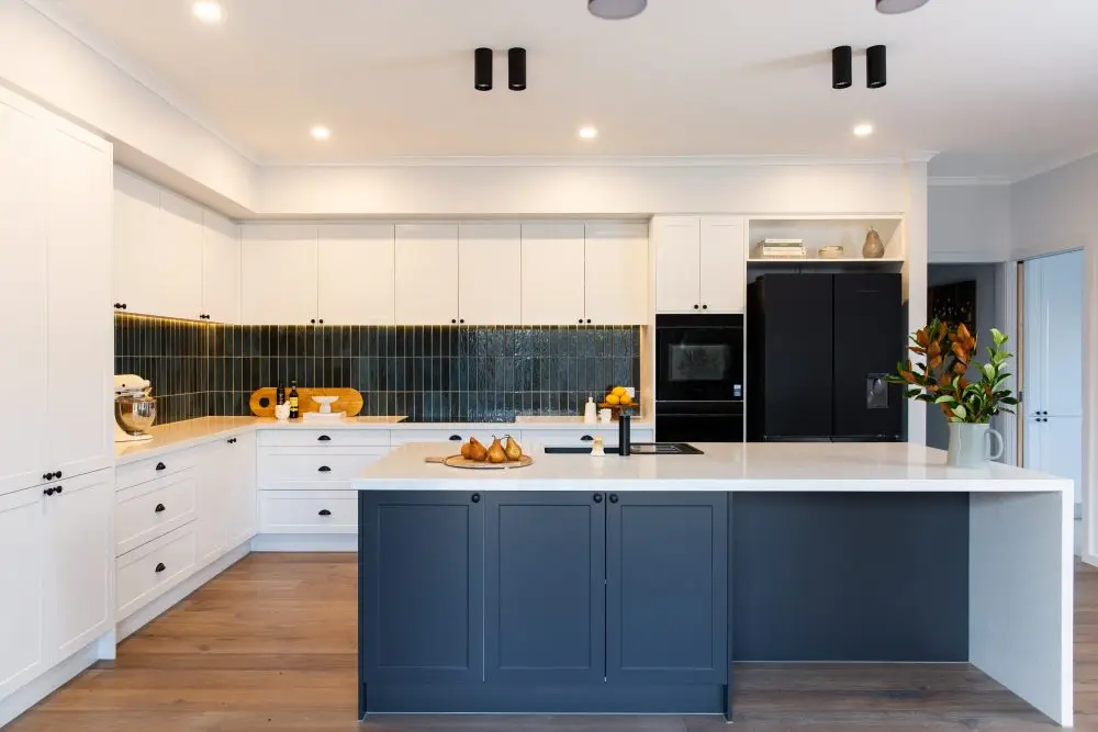 U shaped kitchen with white and grey shaker style cabinetry with large standalone island bench and green tiled splashback