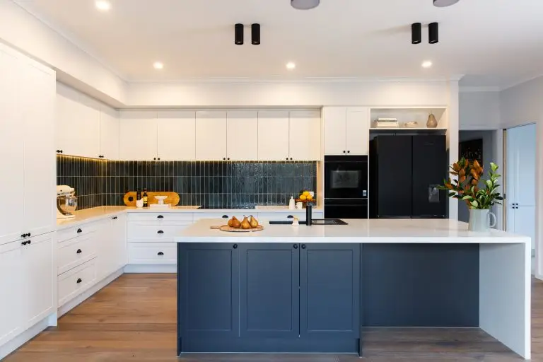 U shaped kitchen with white and grey shaker style cabinetry with large standalone island bench and green tiled splashback