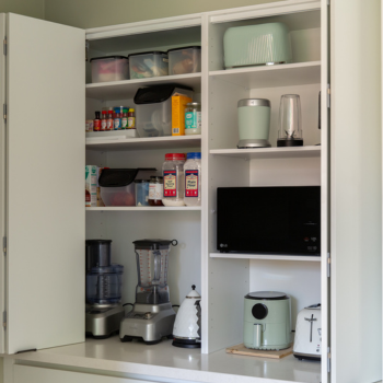 Double door appliance cabinet displaying wingline sliding doors with small appliances inside