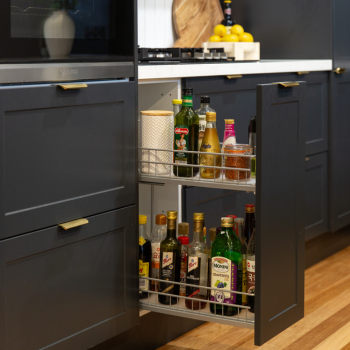 black cabinetry with large pull out spice rack featuring spices sauces and oils