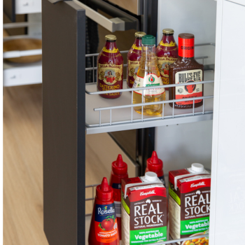 Large pull out spice rack in a kitchen with black cabinetry kitchen door featuring stock and sauces