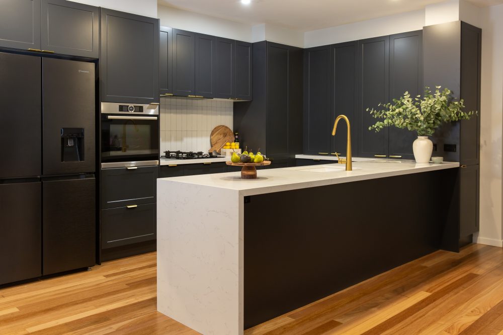 U shaped dark black cabinetry with white benchtops and waterfall ends on island bench