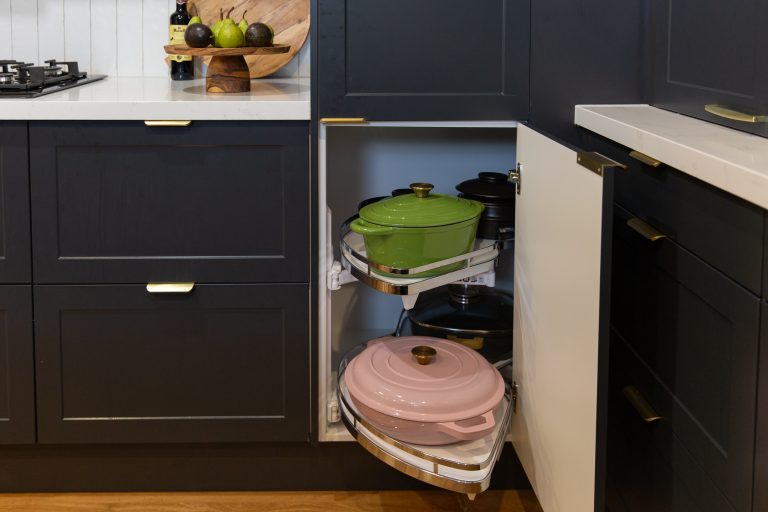 Pull out corner le mans kitchen cabinet displaying a pink and green le creuset pots