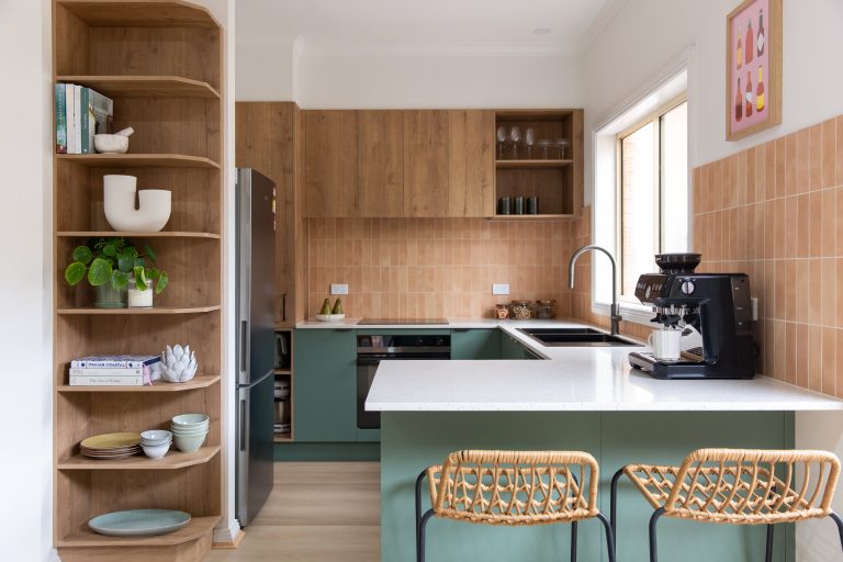 Bottle green and oak timber kitchen with oak and black breakfast bar stools at a stone benchtop