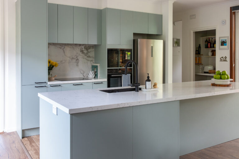 Green and white galley kitchen featuring large island bench with additional storage in the front