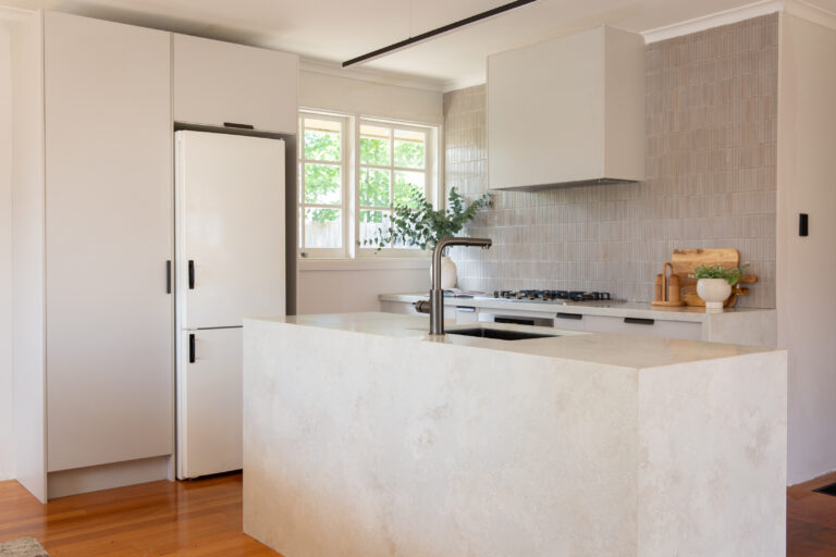 White kitchen cabinetry with large island bench complete in stone including waterfall ends