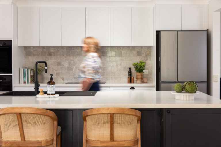 Lady walking through a white and dark grey shaker style galley kitchen