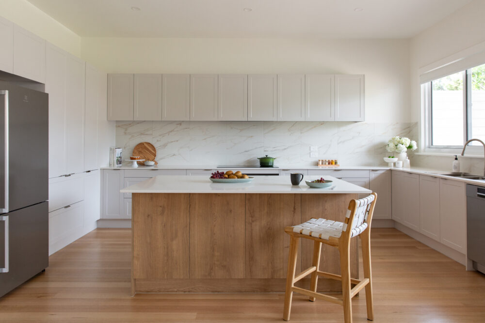 Light grey Shaker cabinetry matched with oak cabinetry under island bench in a large u shaped galley kitchen