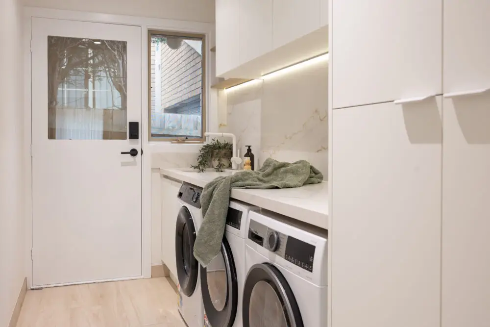 Galley white laundry with side by side washer dryer and tall linen cupboard with white handles