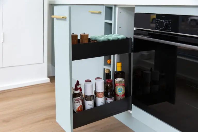 Pull out spice rack in green kitchen cabinet with black interior