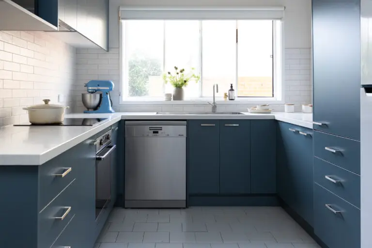 U shaped blue colour kitchen with chrome handles, dishwasher and induction cooktop with pot