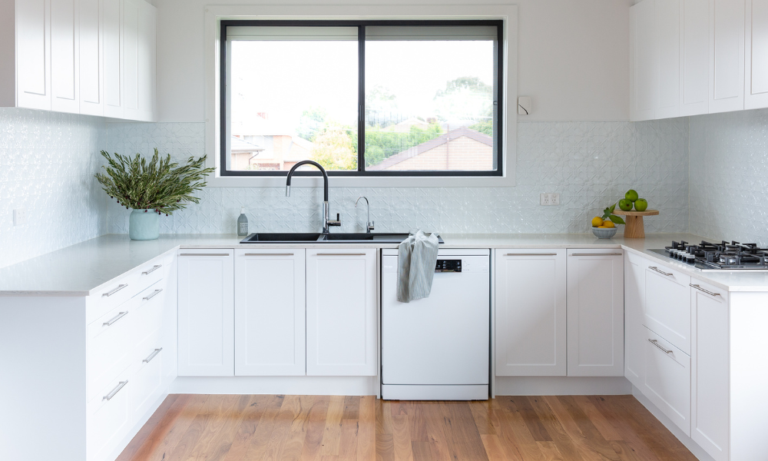 White u shape kitchen with chrome handles and black sink and tap and cooktop and featuring tin splashback and fruit and folliage for kitchen bench styling