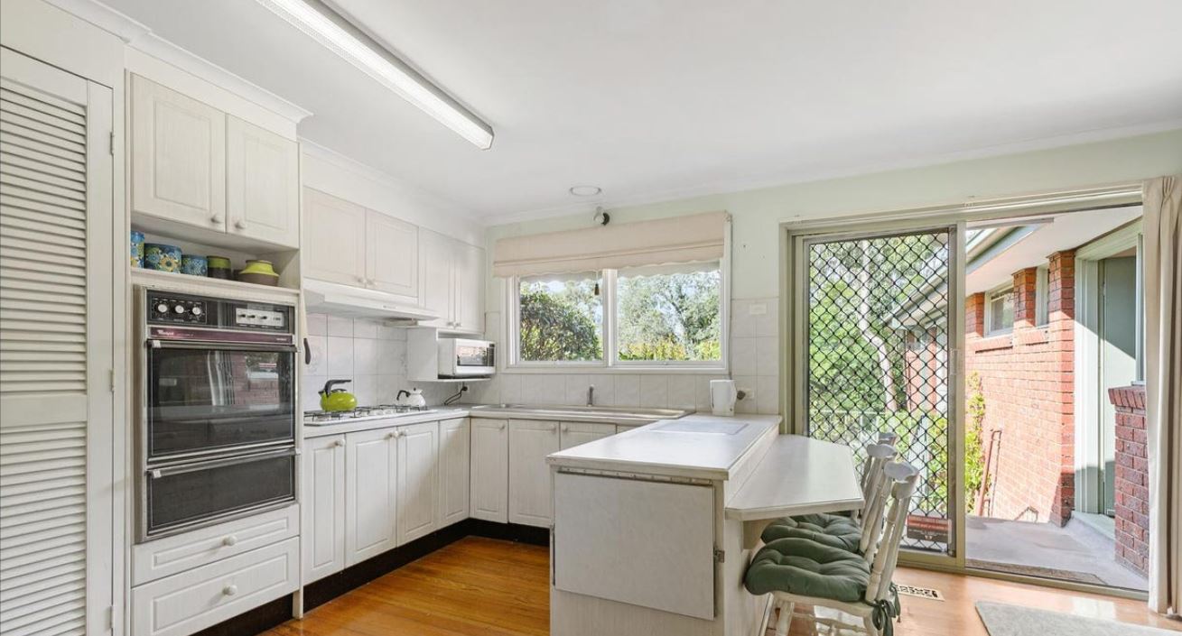 Older style white cabinetry u shape kitchen wiht black wall oven tower