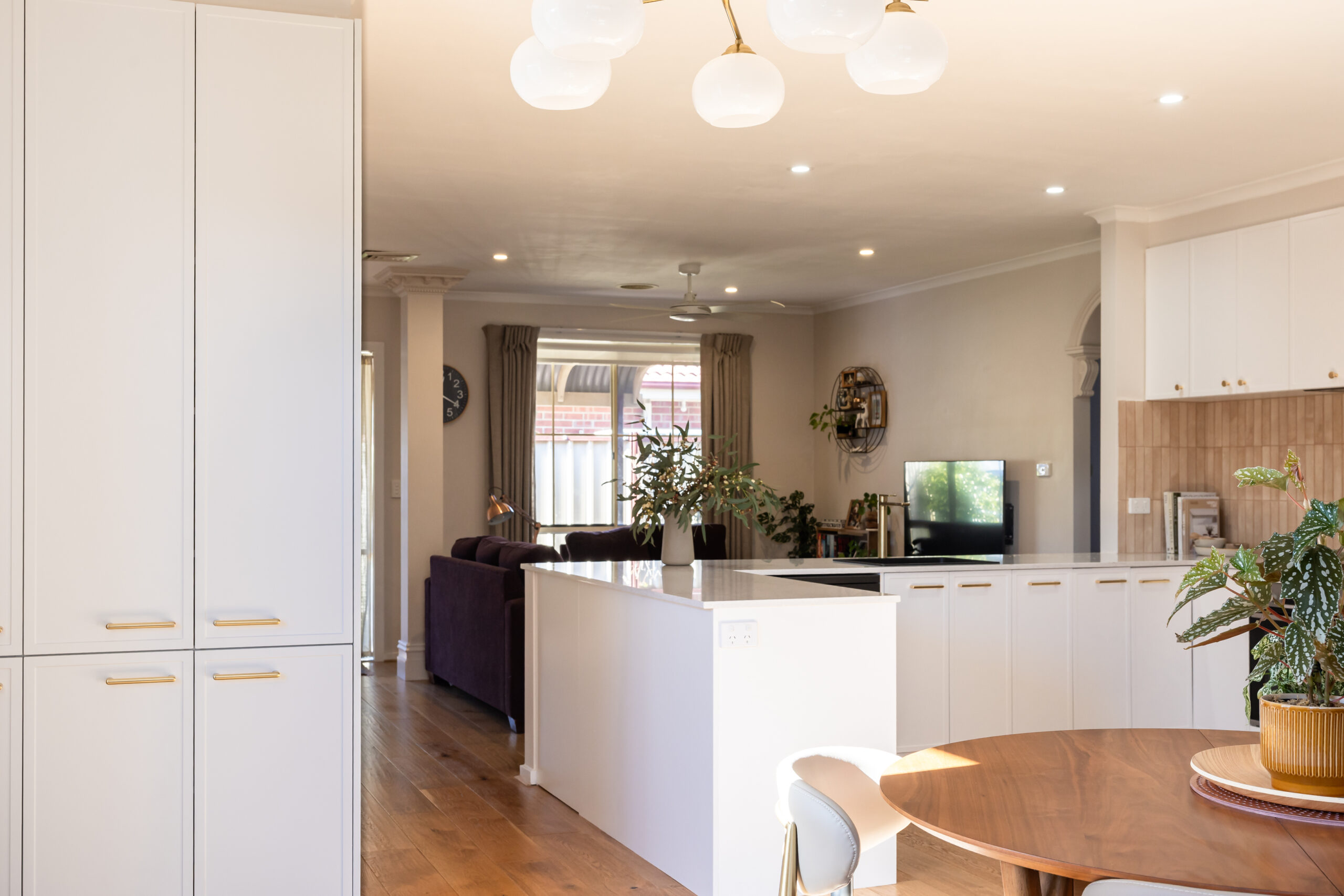 L shape kitchen in white Hampton style cabinetry with pantry with brass handles