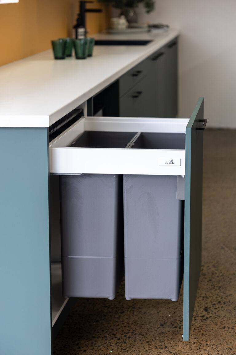 Green kitchen featuring double pull out bin system