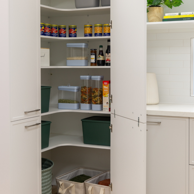 Corner pantry in parchment kitchen cabinetry with jars, tin food and basket storage inside