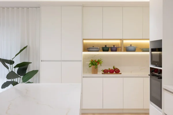 White handle free kitchen featuring white cupboards with timber feature shelving with styling pots and vase with flower