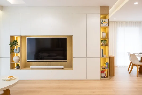 Living room cabinetry displaying a large wall of handle free white and birch laminate cabinetry with styling items in open shelf at the end