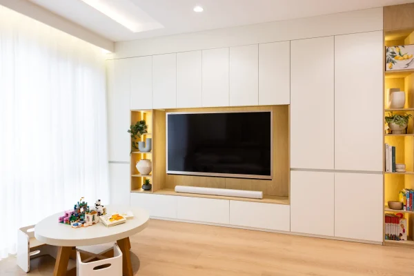 Living room cabinetry in white and timber laminate with vases and kids play table and chairs