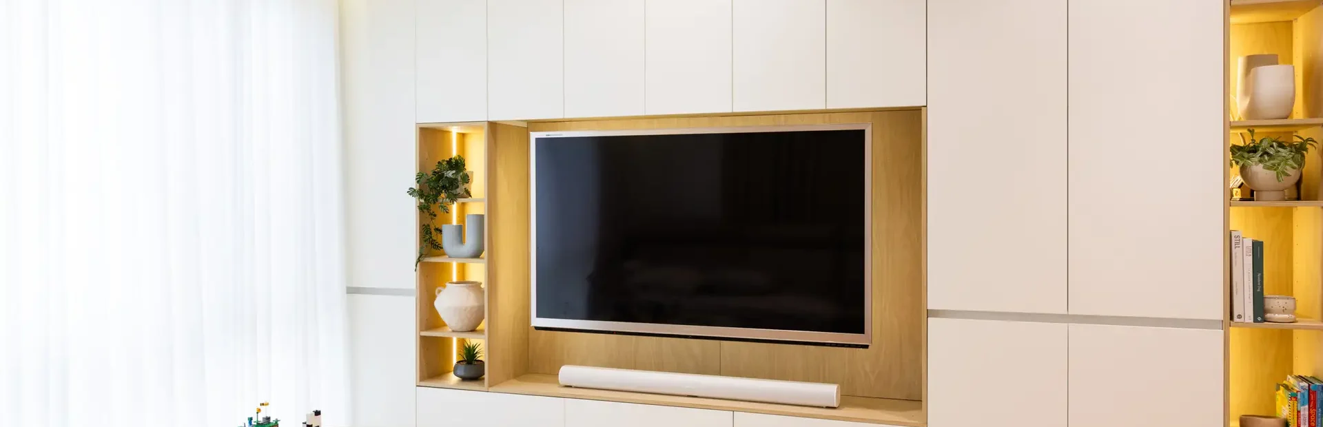 Living room cabinetry in white and timber laminate with vases and kids play table and chairs