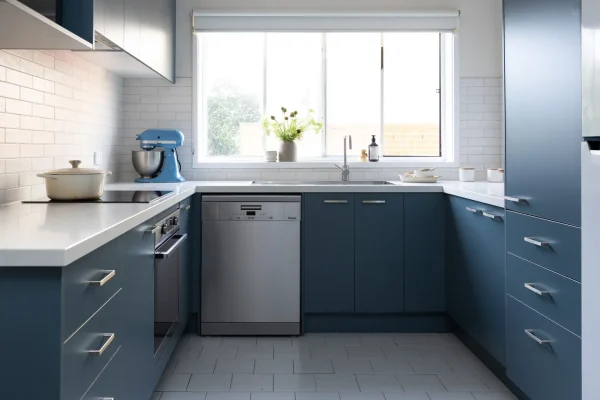 U shaped blue colour kitchen with chrome handles, dishwasher and induction cooktop with pot