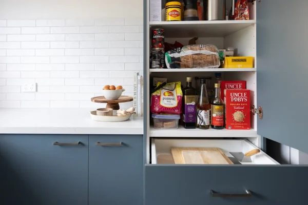 Kitchen featuring tall pantry with pantry items with blue cabinetry and white stone benchtops with eggs on bench