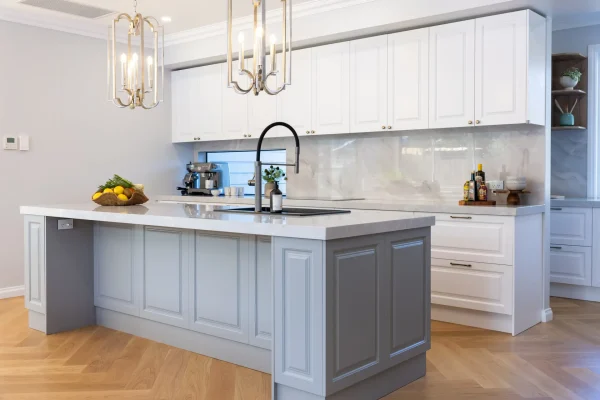 Carrington Shaker style kitchen with white cabinetry featuring grey large island with gooseneck tap and stone benchtops, gold pendant lights and herringbone timber flooring