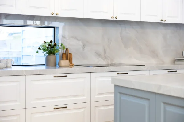 White and grey kitchen cabinetry in carrington style with chrome kitchen handles and stone benchtops and splashbacks