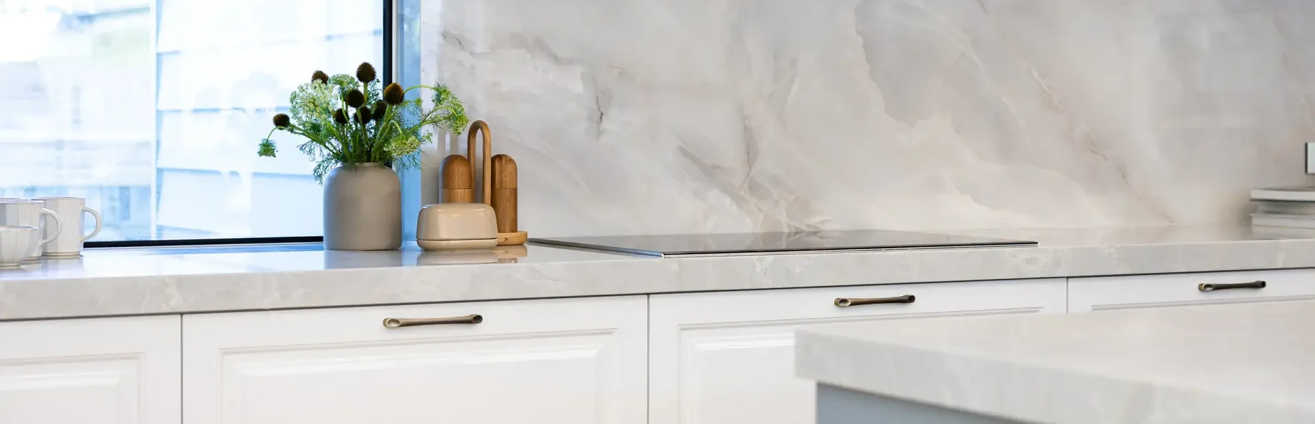White and grey kitchen cabinetry in carrington style with chrome kitchen handles and stone benchtops and splashbacks