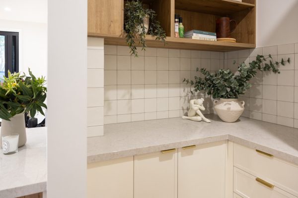 Butlers pantry featuring white hampton cabinetry with oak timber laminate shelving and styling items like cookbooks, plants and ornaments