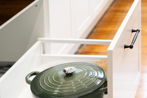 White shaker style kitchen pot drawer with black handle and green cookpot