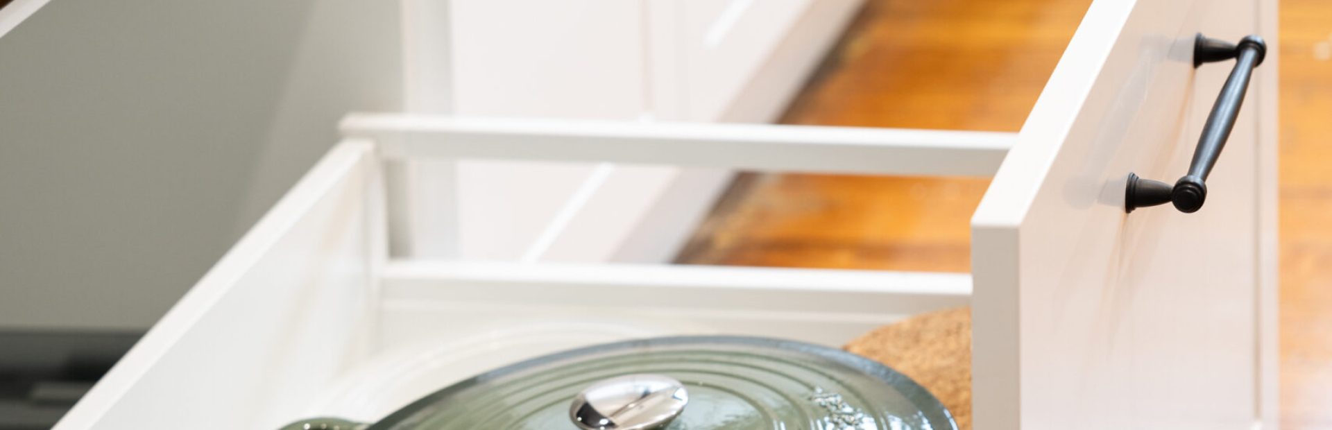 White shaker style kitchen pot drawer with black handle and green cookpot