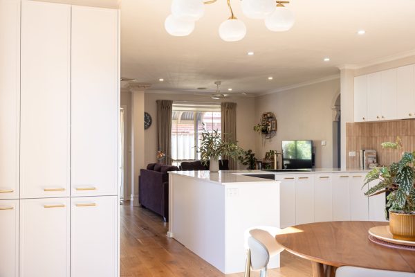 White kitchen in hampton style with brass handles displaying timber round dining table