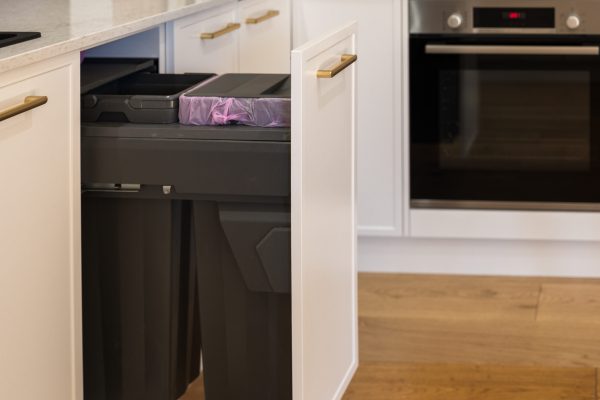 Pull out double kitchen bins in black housed in a white hampton style kitchen with brass handles