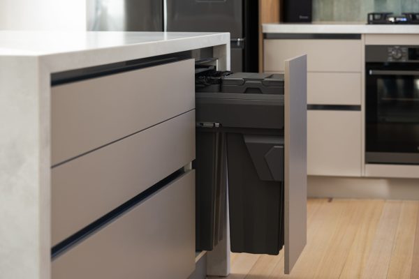Kitchen cabinetry pot drawers in beige with handle free displaying pull out bin in dark grey