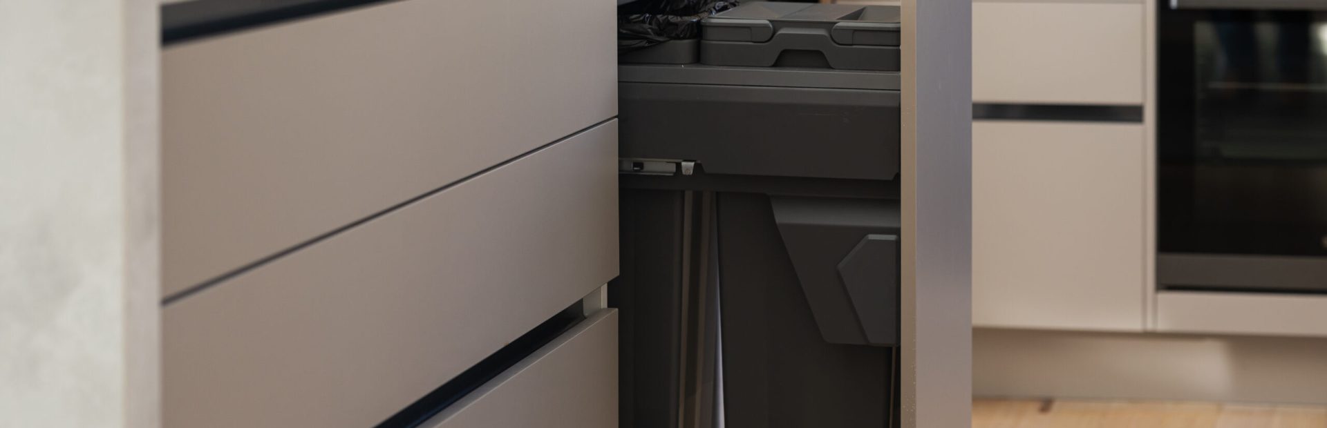 Kitchen cabinetry pot drawers in beige with handle free displaying pull out bin in dark grey